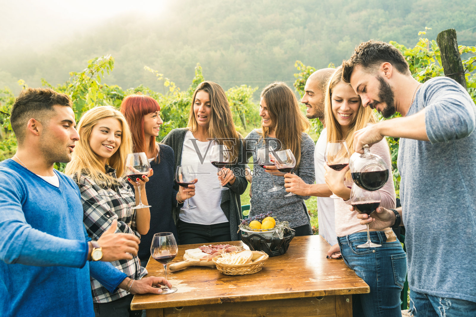 一群快乐的朋友在户外喝红酒-年轻人吃当地的新鲜食物在农家葡萄园葡萄收获-青年友谊概念上生动的温暖过滤器照片摄影图片