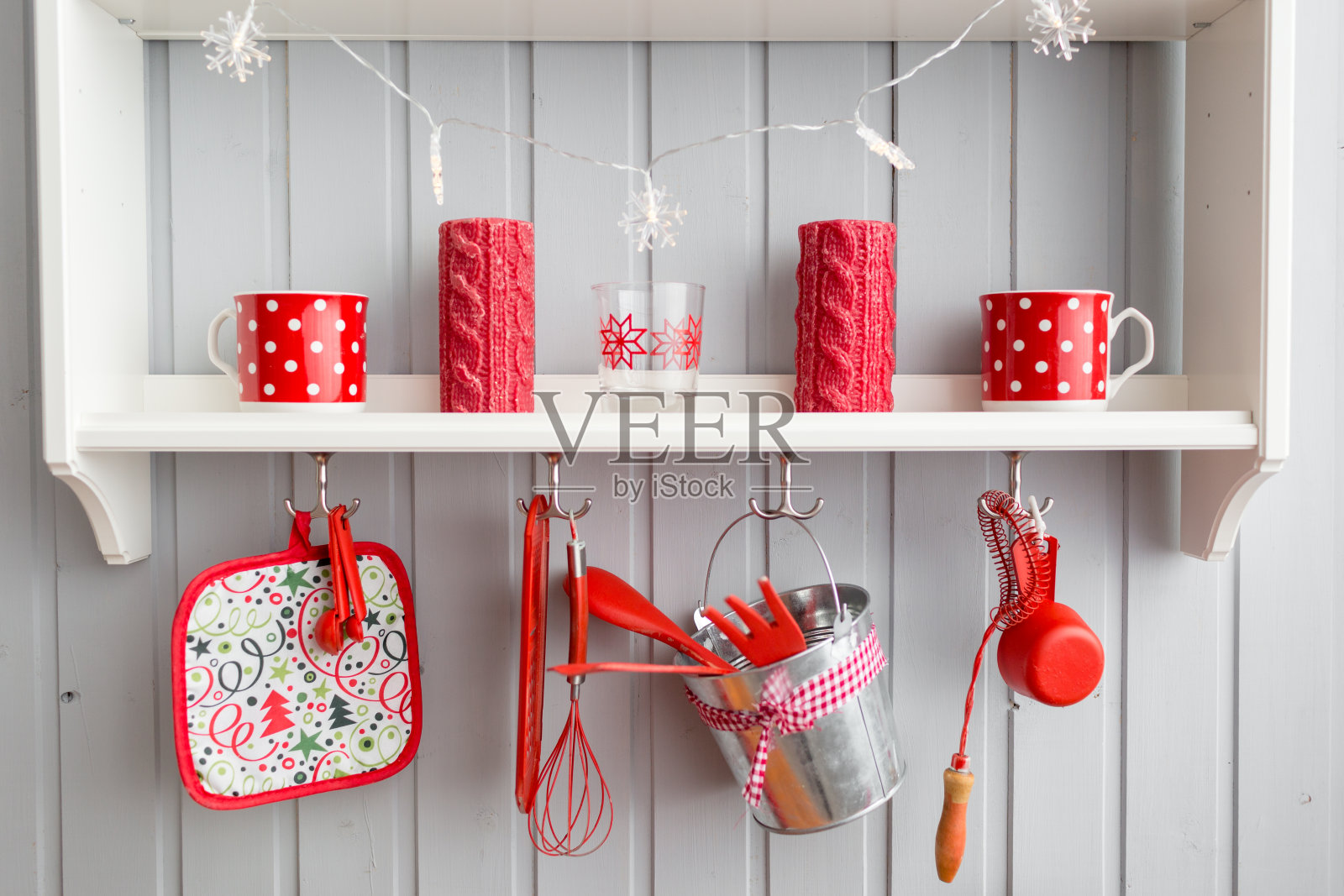 货架与菜肴。室内浅灰色的厨房和红色的圣诞装饰。用厨房的概念在家准备午餐。照片摄影图片