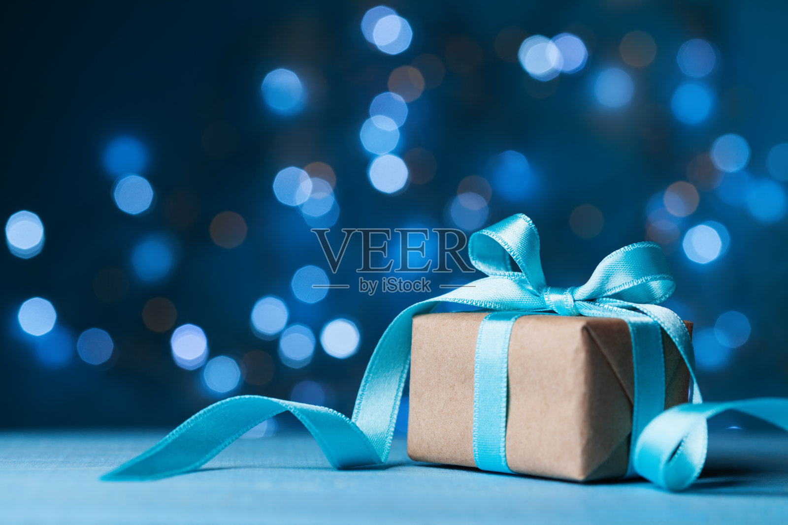 圣诞礼盒或礼物与蝴蝶结丝带在魔术蓝色散景背景。照片摄影图片