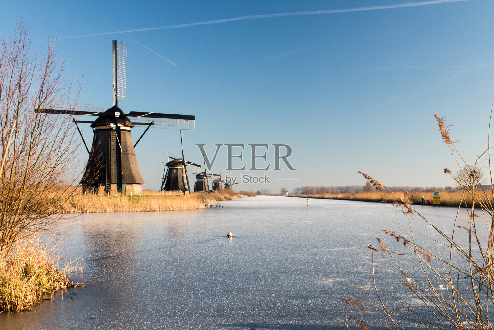 荷兰的肯德戴克公园，在荷兰的冬天有结冰的运河。运河里有风车和冰，还有褐色的植被照片摄影图片