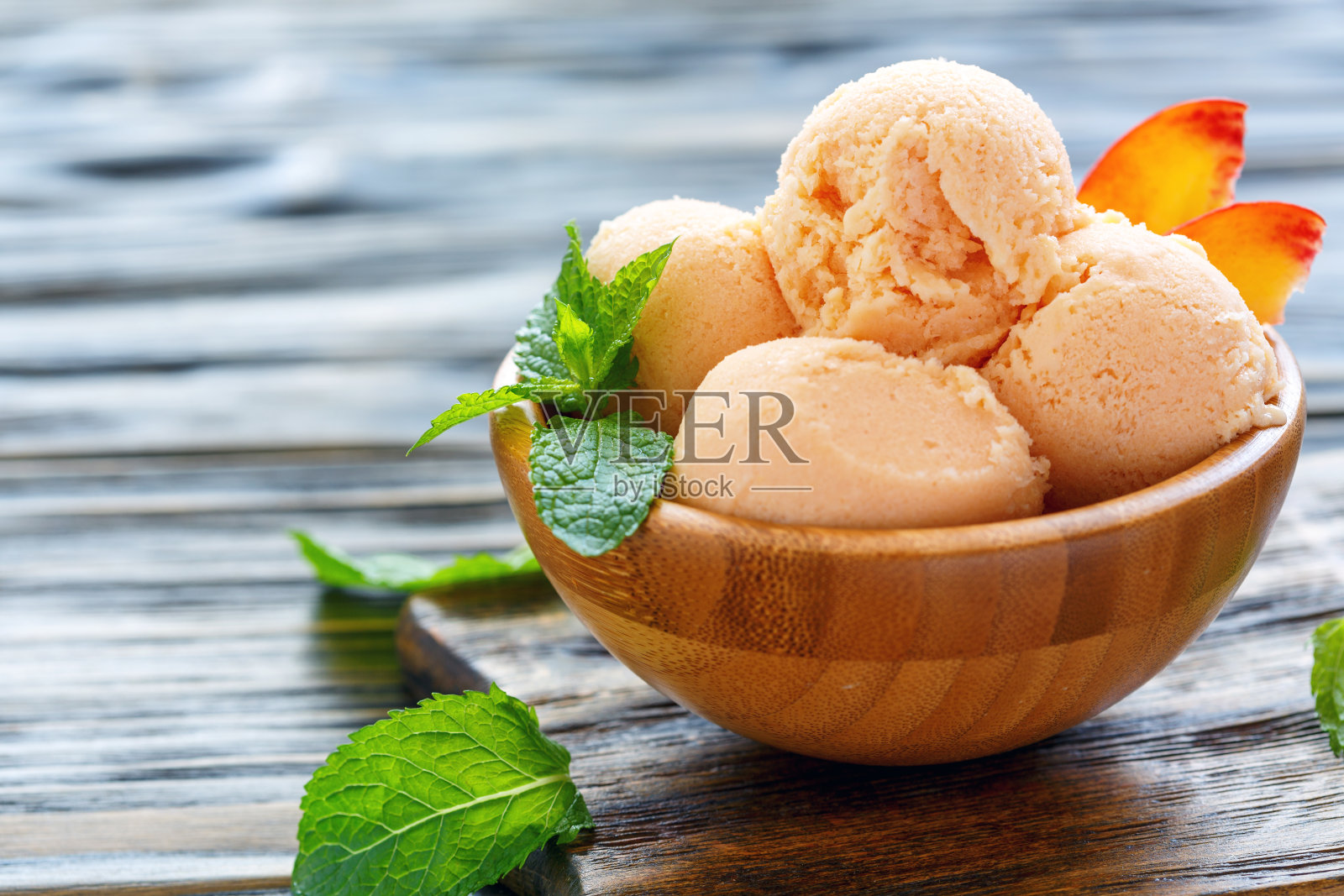 球桃子冰淇淋在一个木碗。照片摄影图片