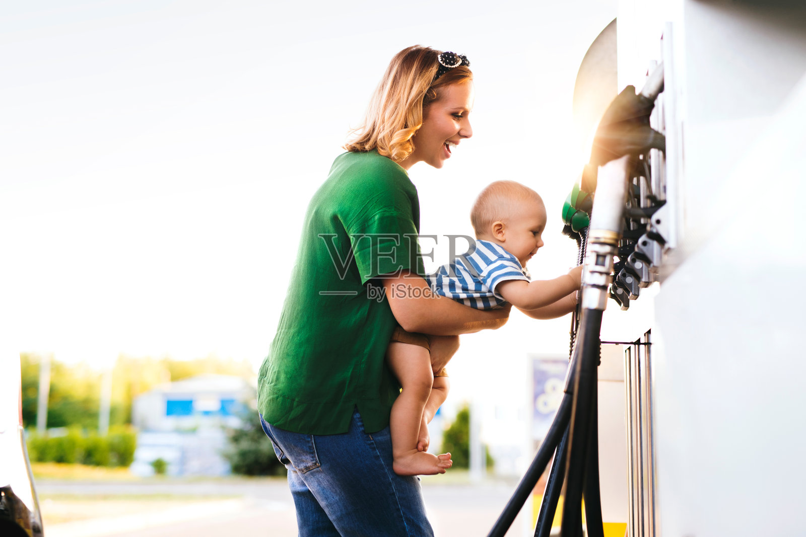 年轻的母亲带着男婴在加油站。照片摄影图片