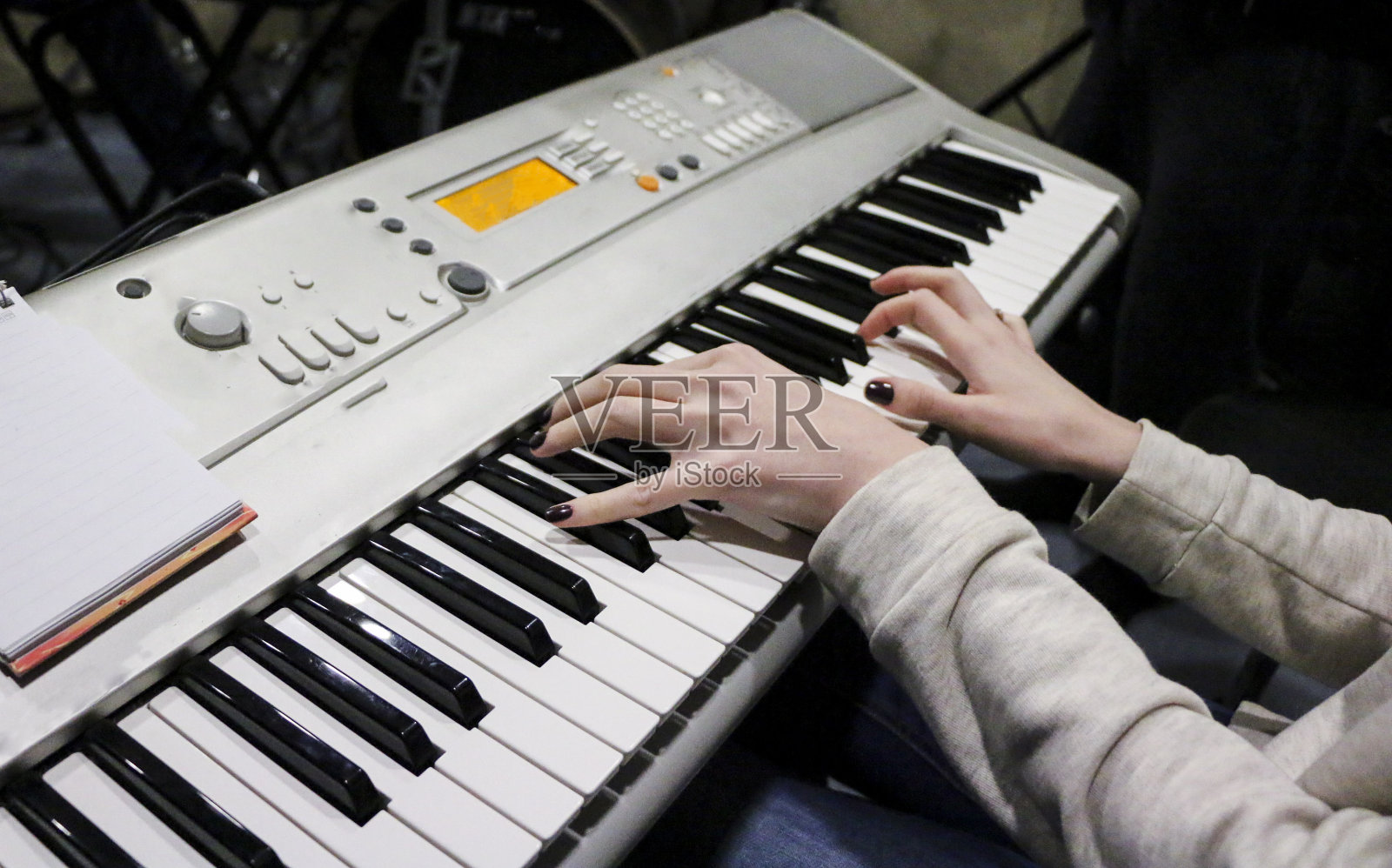 一位年轻的钢琴家弹奏着她最喜欢的音乐的电子钢琴。女性优雅的手触摸键盘的合成器特写。照片摄影图片