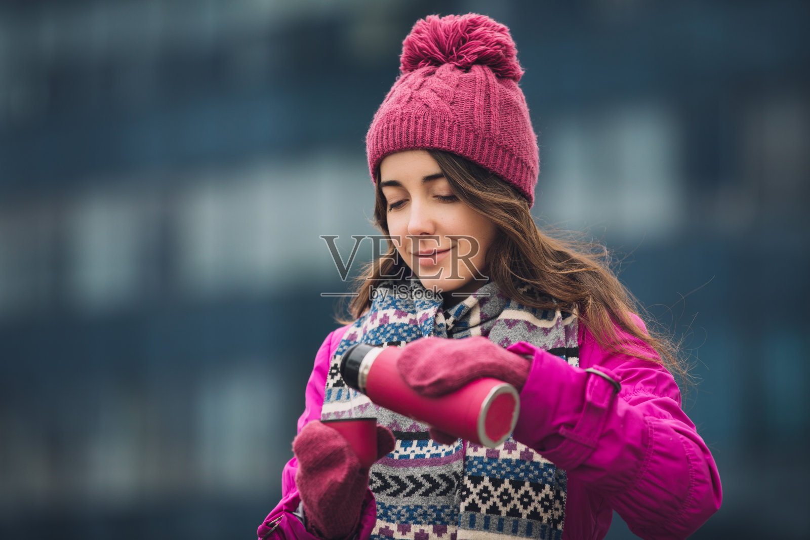 穿着鲜艳冬季夹克的女人在室外往热水瓶里倒茶照片摄影图片