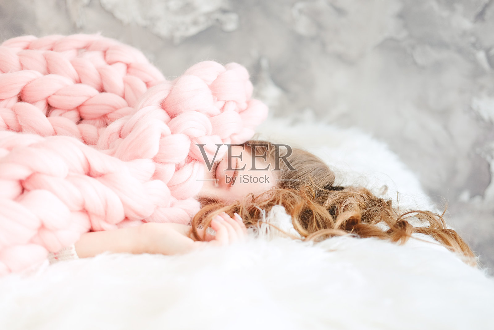 年轻女子与长棕色头发睡在温暖针织桃色扔毯子照片摄影图片