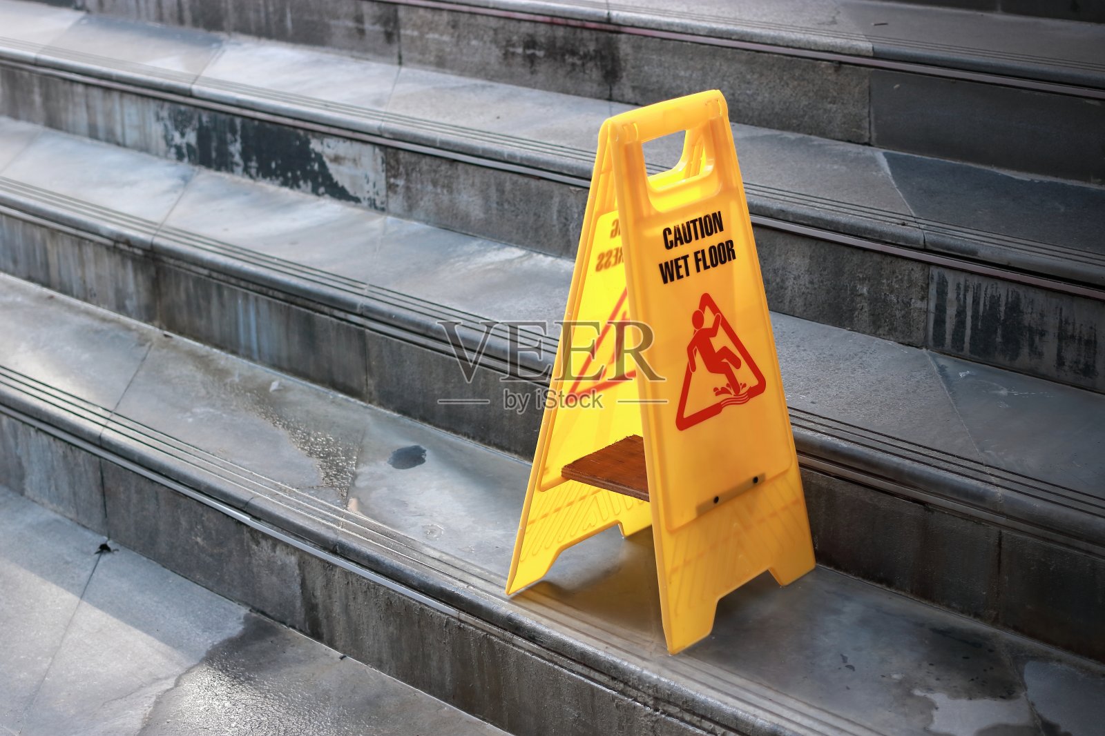 室外城市楼梯黄色警告湿地板标志。照片摄影图片