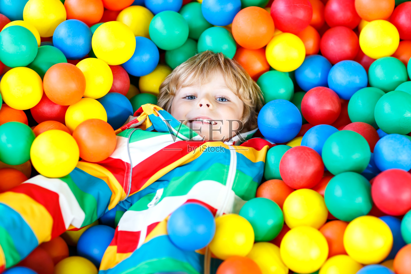 一个小男孩在操场上玩五颜六色的塑料球照片摄影图片