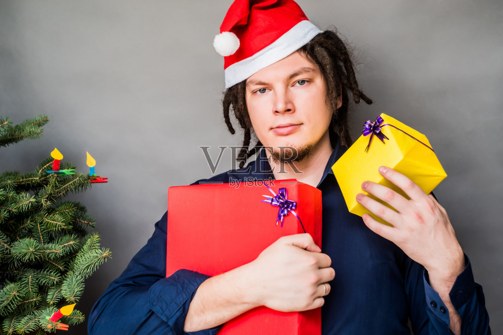 年轻人戴着圣诞帽，拿着两份圣诞礼物照片摄影图片