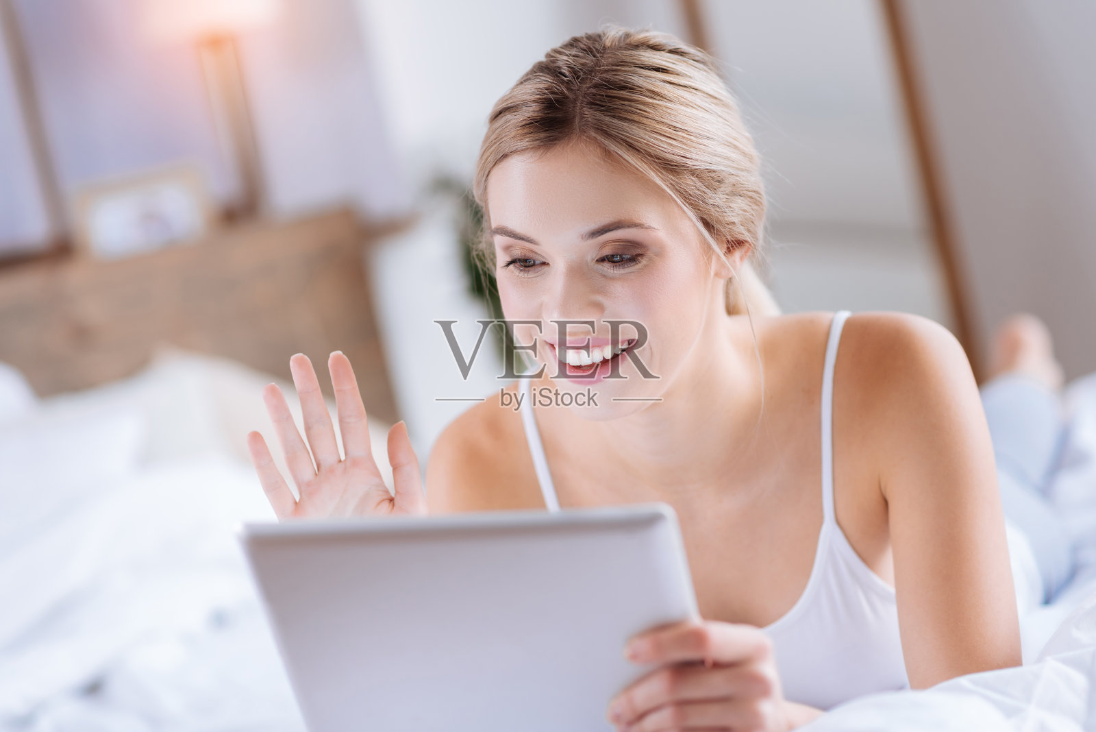 开朗的金发女人正在用平板电脑打视频电话照片摄影图片