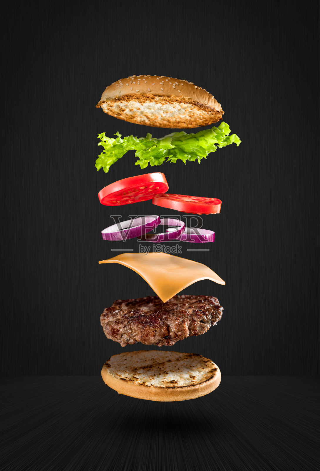 美味的汉堡与飞行的配料在黑色的背景照片摄影图片
