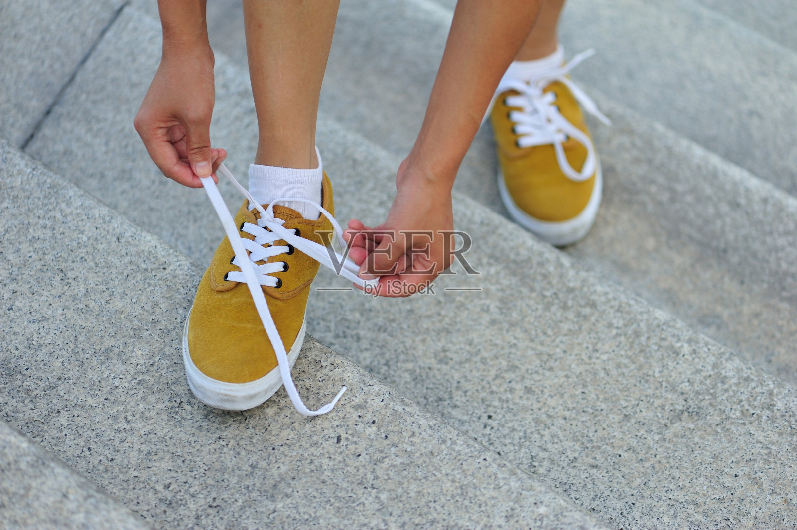 年轻女子双手系着鞋带站在城市的楼梯上照片摄影图片