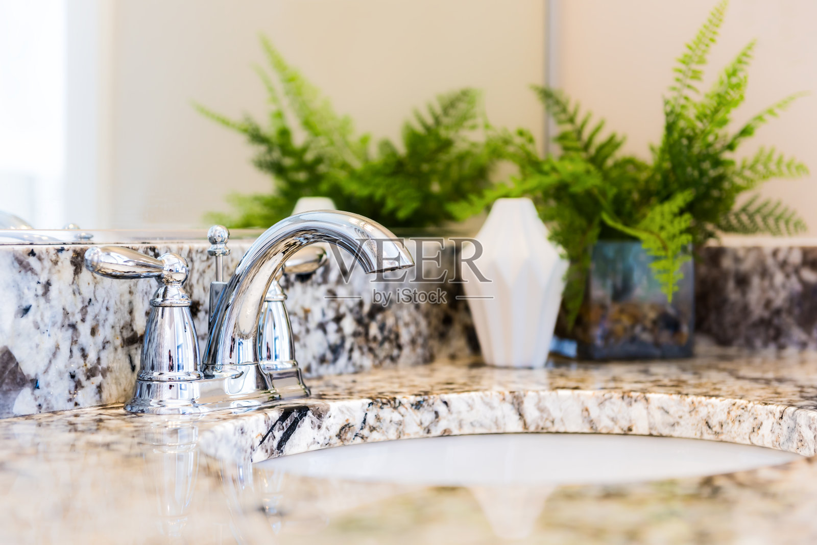 特写的现代浴室水槽与中性花岗岩台面和镜子，绿色植物在花盆照片摄影图片