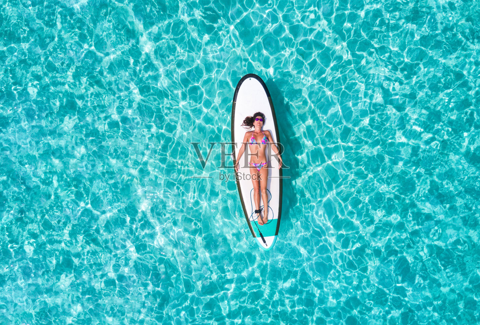 穿着比基尼的女人正在冲浪板上晒太阳照片摄影图片
