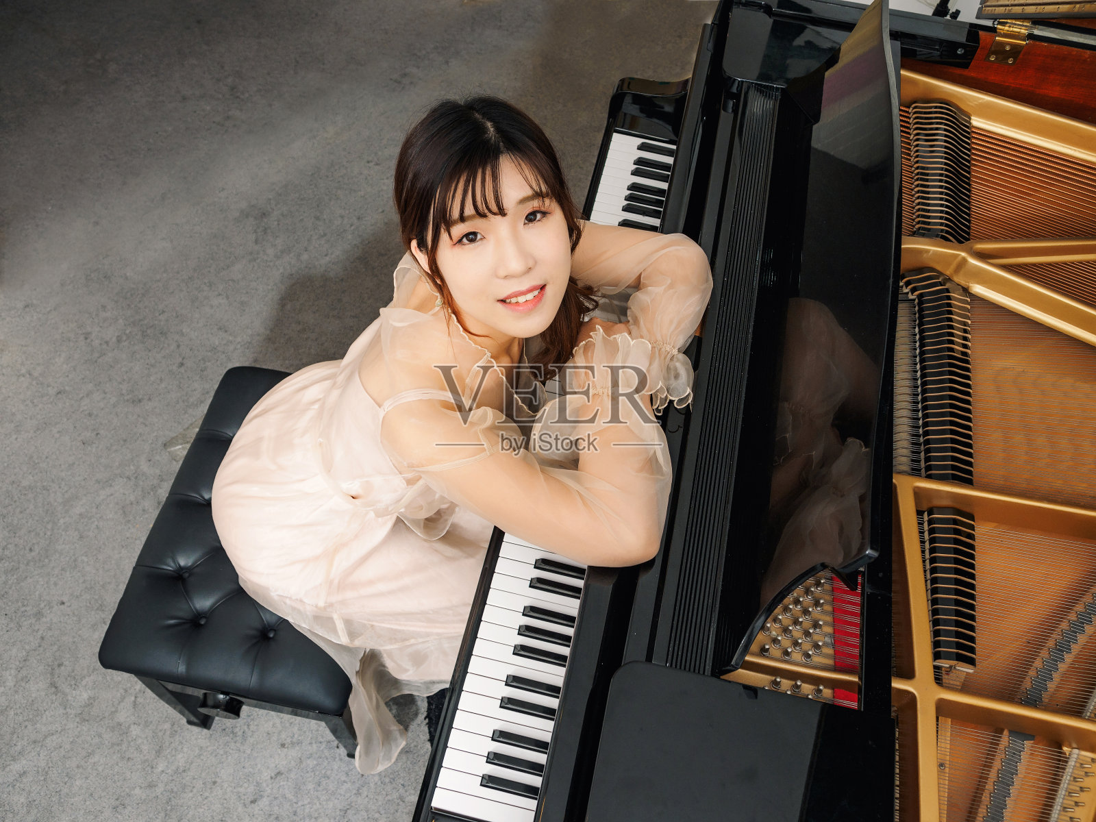 中国女孩和大钢琴。漂亮的年轻女孩钢琴家。照片摄影图片