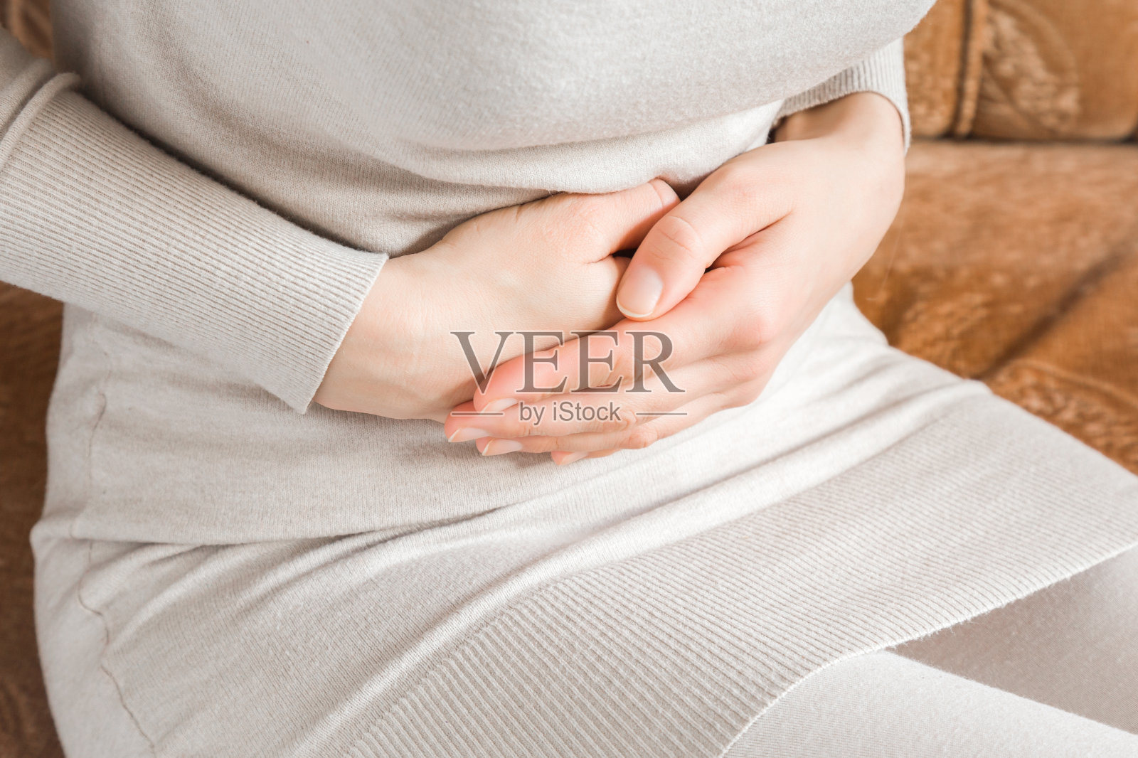 女人的手抚摸着她的肚子，因为她在家里的床上忍受着腹痛。胃痛问题及解决概念。照片摄影图片