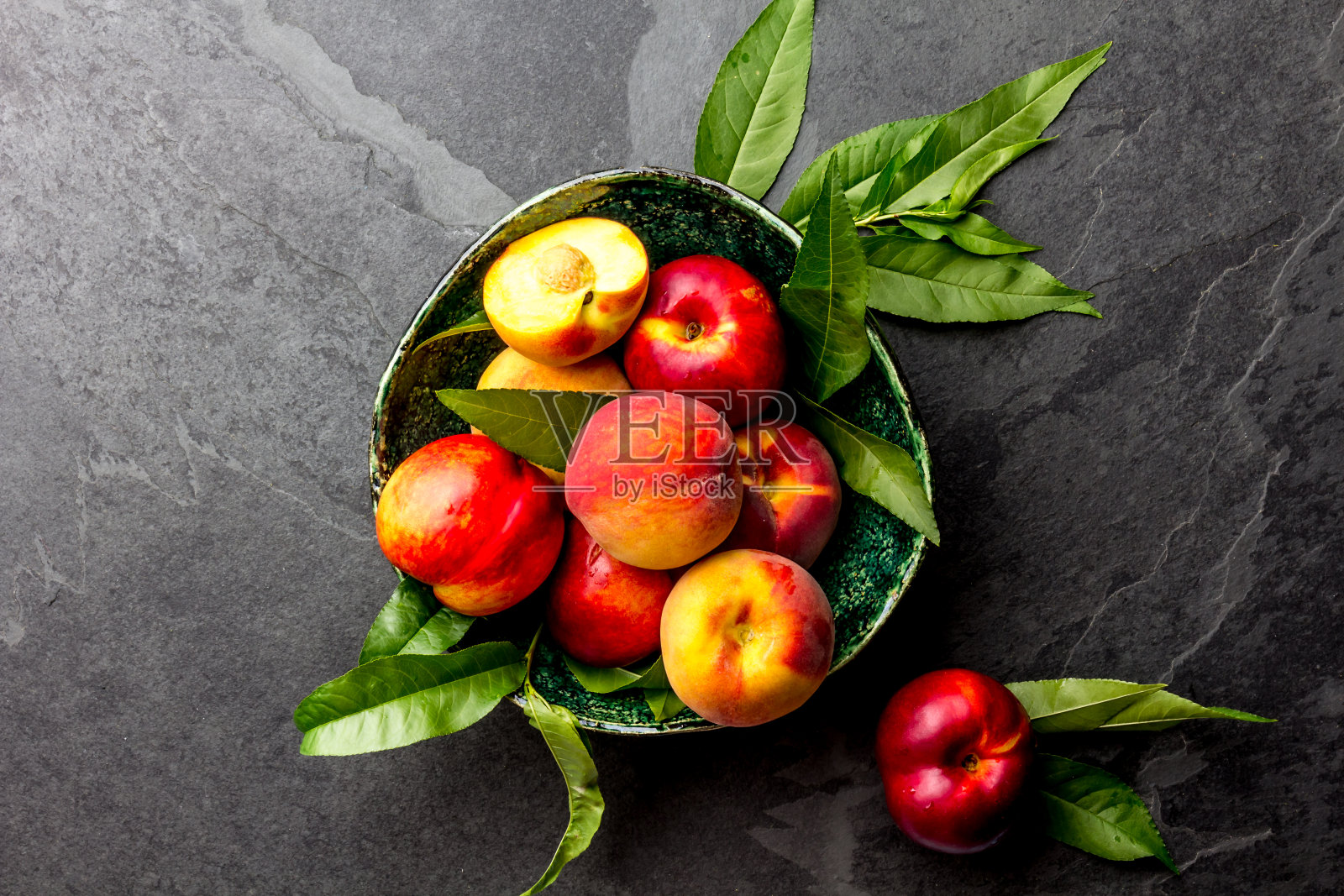 新鲜成熟的桃子与桃树的叶子呈绿色碗状，俯视图照片摄影图片