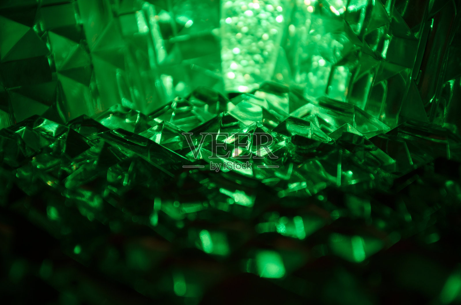 近距离切割水晶在神秘的绿宝石光。神奇的背景。照片摄影图片