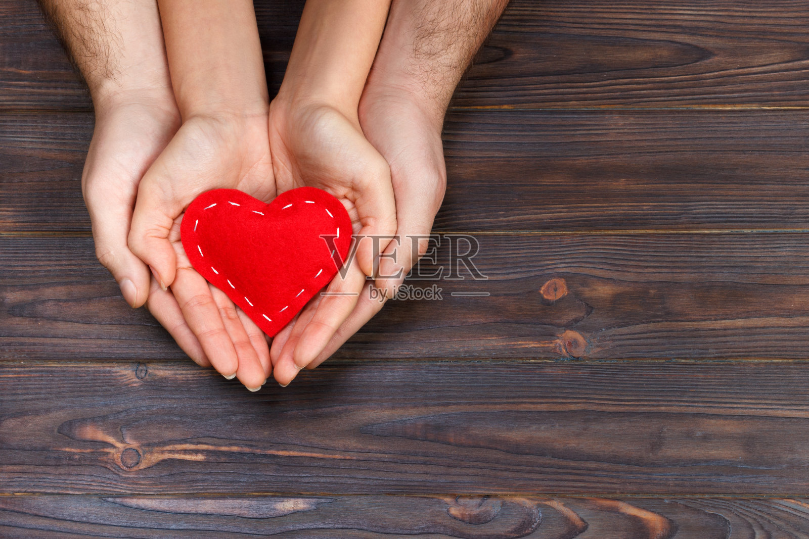爱情、家庭的概念。近距离的男人和女人的手握着红色的橡胶心在一起照片摄影图片