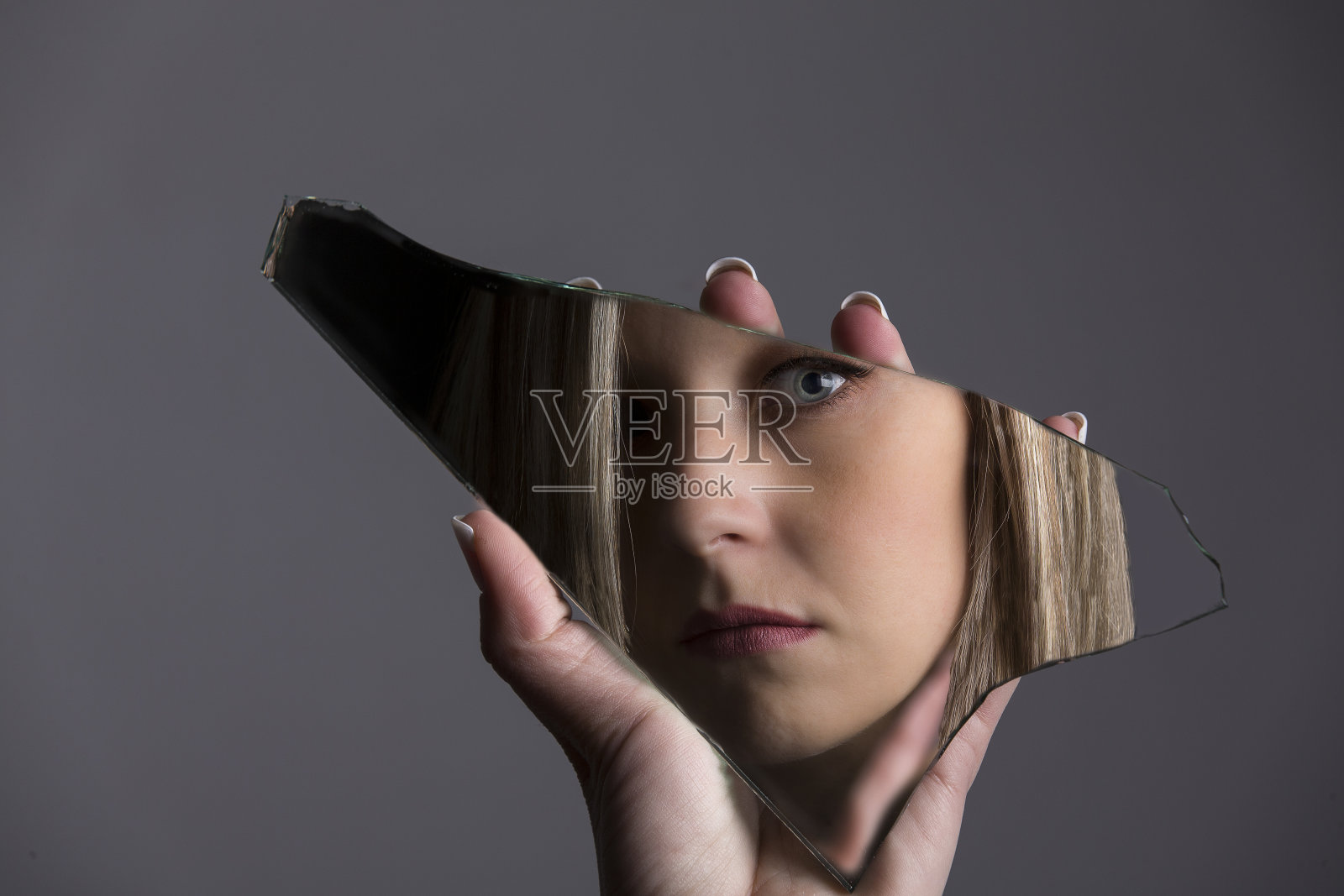 一个女人看着自己的脸在破碎的镜子碎片里照片摄影图片