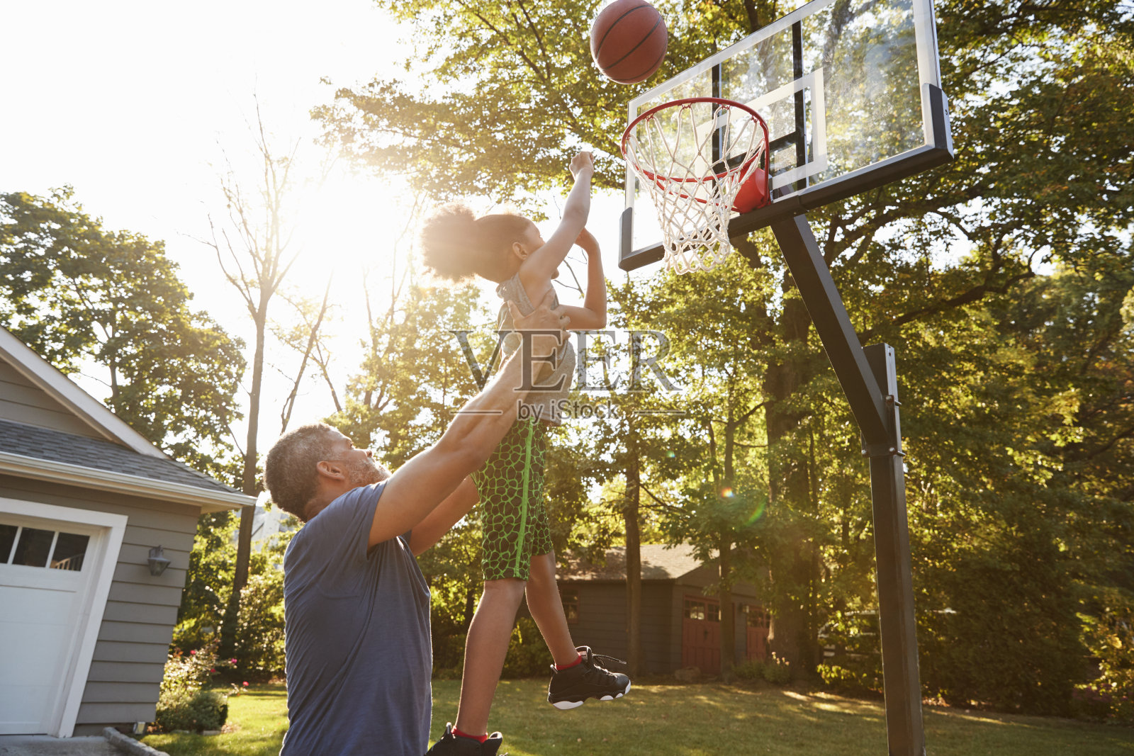 爸爸和儿子在家里的车道上打篮球照片摄影图片