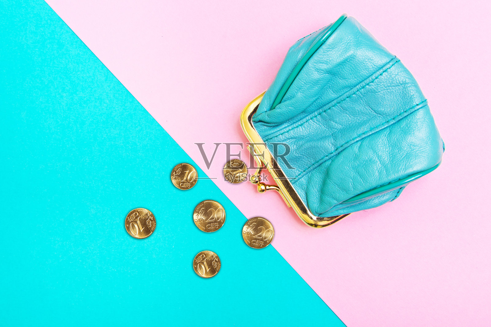 钱包里的硬币。一个皮革钱包，钱包上的几何粉色和绿松石背景。趋势的颜色。照片摄影图片