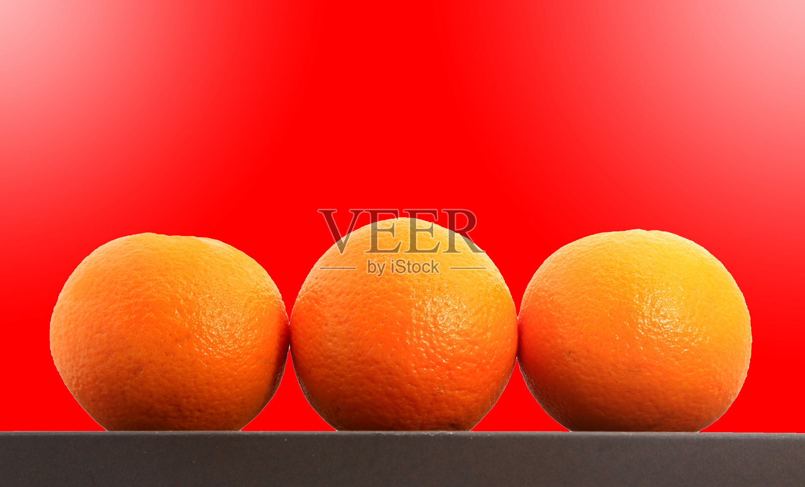 三个橘子从红色的背景上射出照片摄影图片