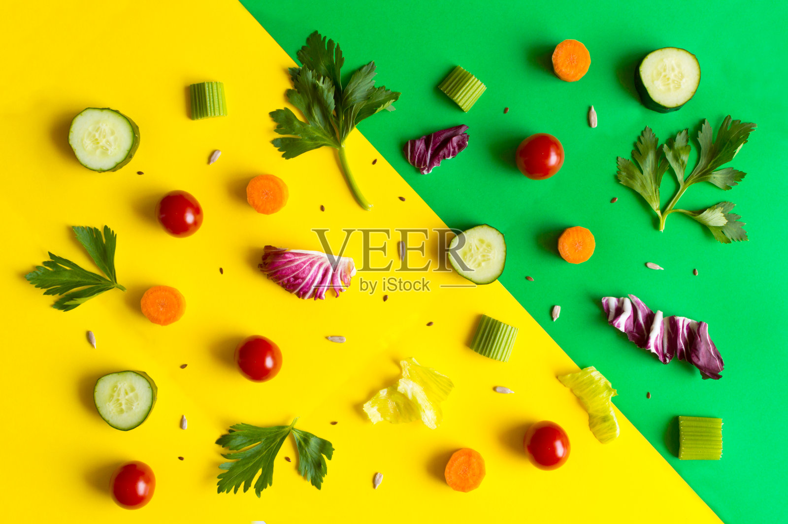 食材包括沙拉、生菜叶、黄瓜、红番茄、胡萝卜、芹菜等，以色彩缤纷的绿色和黄色为背景照片摄影图片