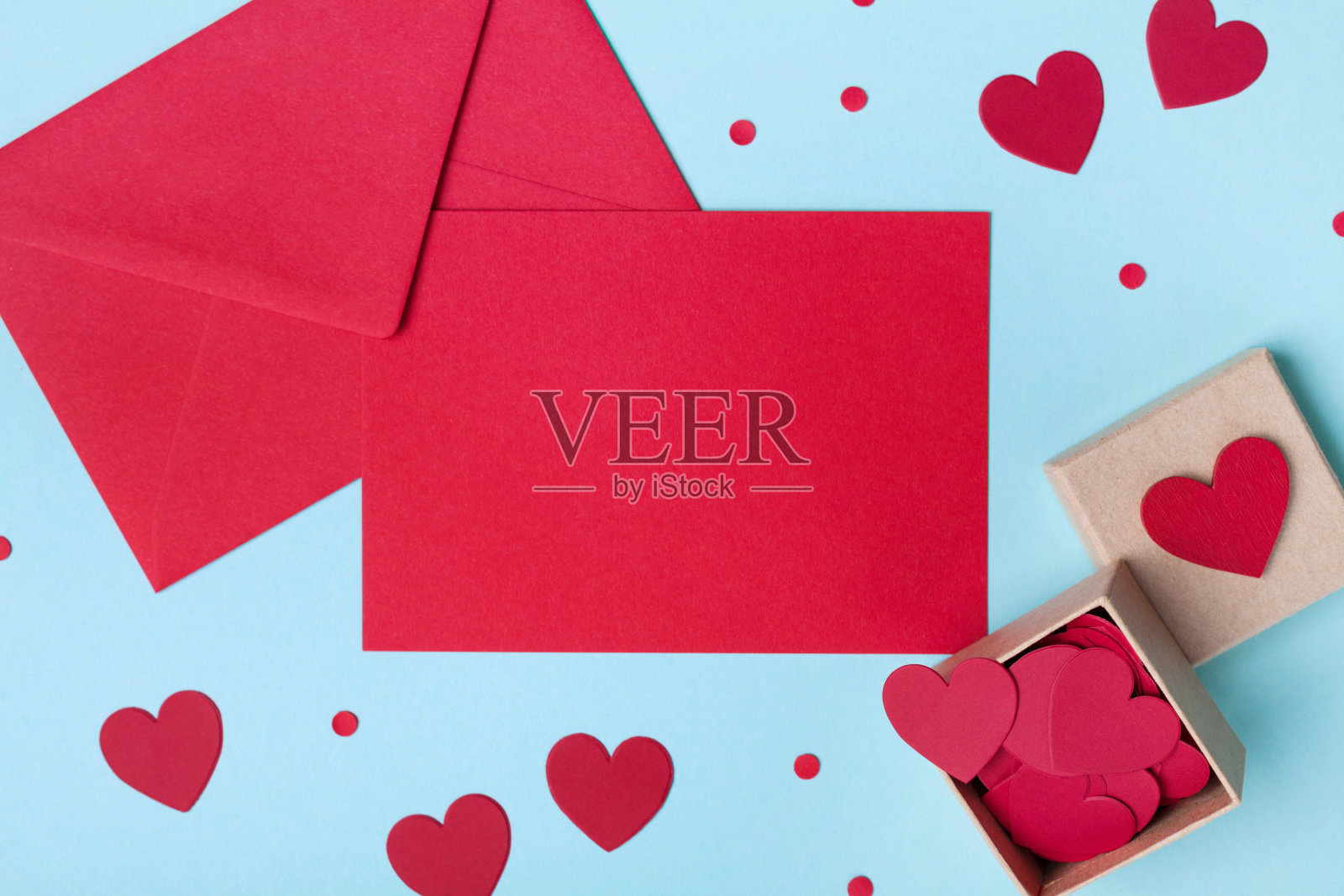 情人节的节日模型。盒子里装满了红色的心和纸卡与信封上的蓝色桌子顶视图。照片摄影图片