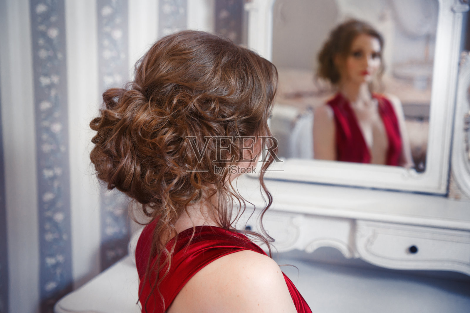 镜子里映出一个梳着漂亮发型的女孩。照片摄影图片