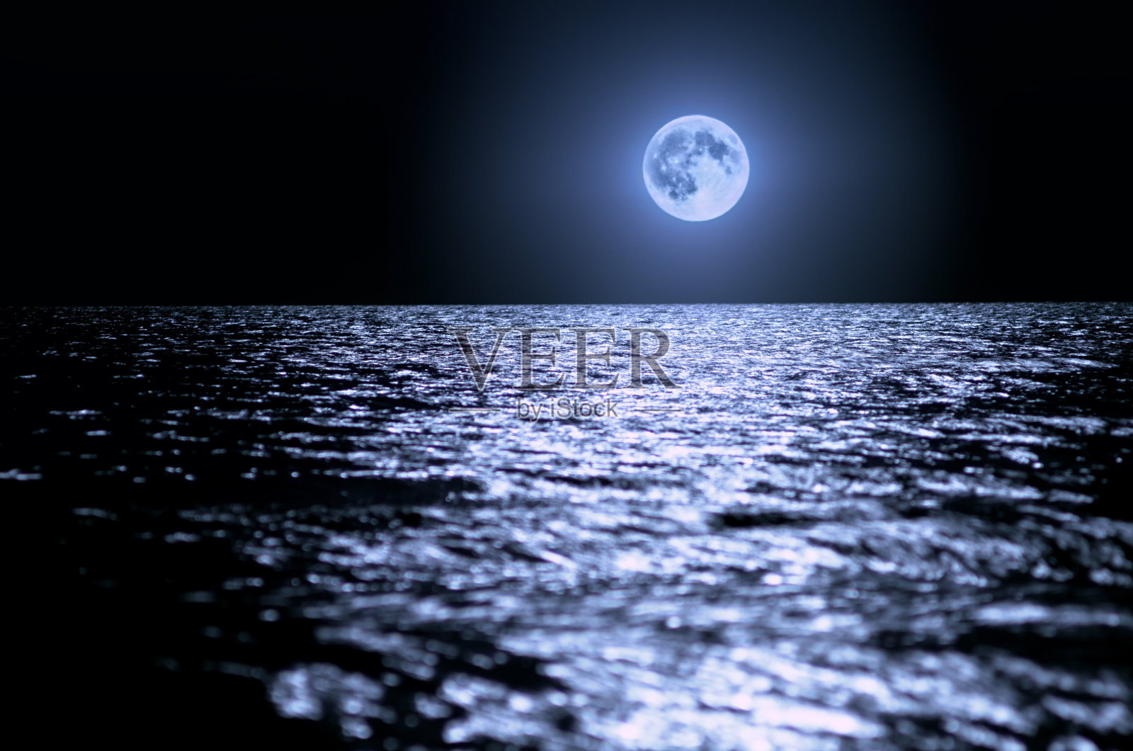 晚上海上有一轮大月亮。月光洒在水波上，地平线上。照片摄影图片