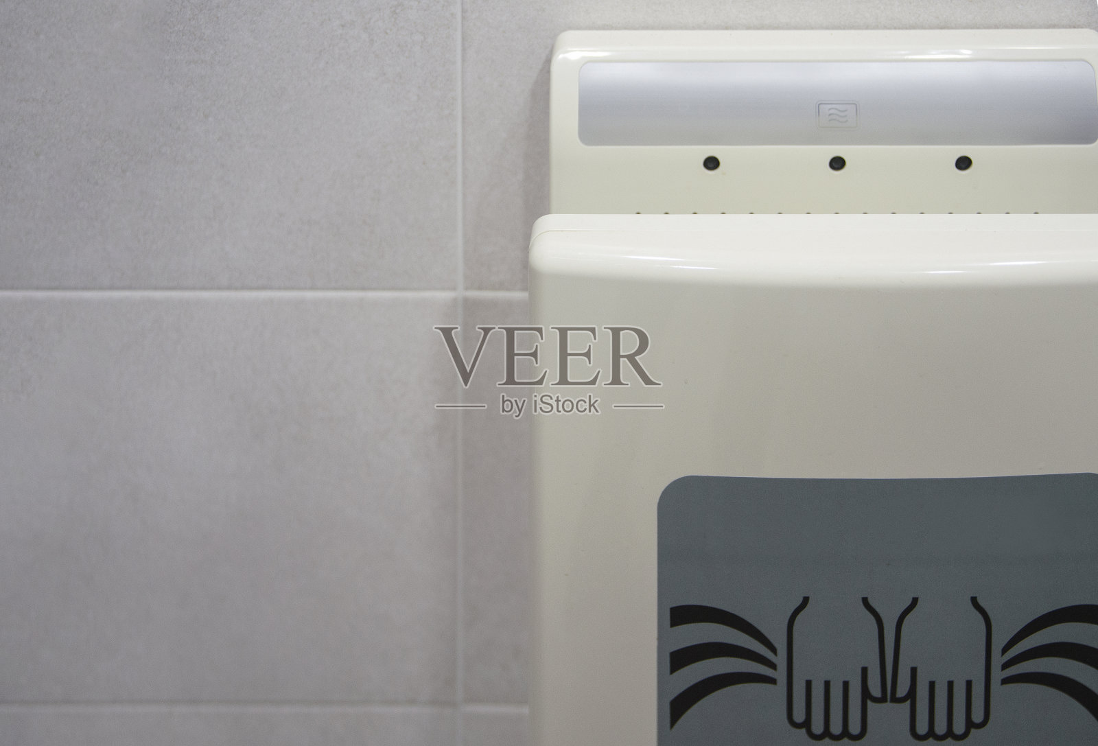 在公共厕所安装的烘手机-在烘手机产品上有一个标志。照片摄影图片