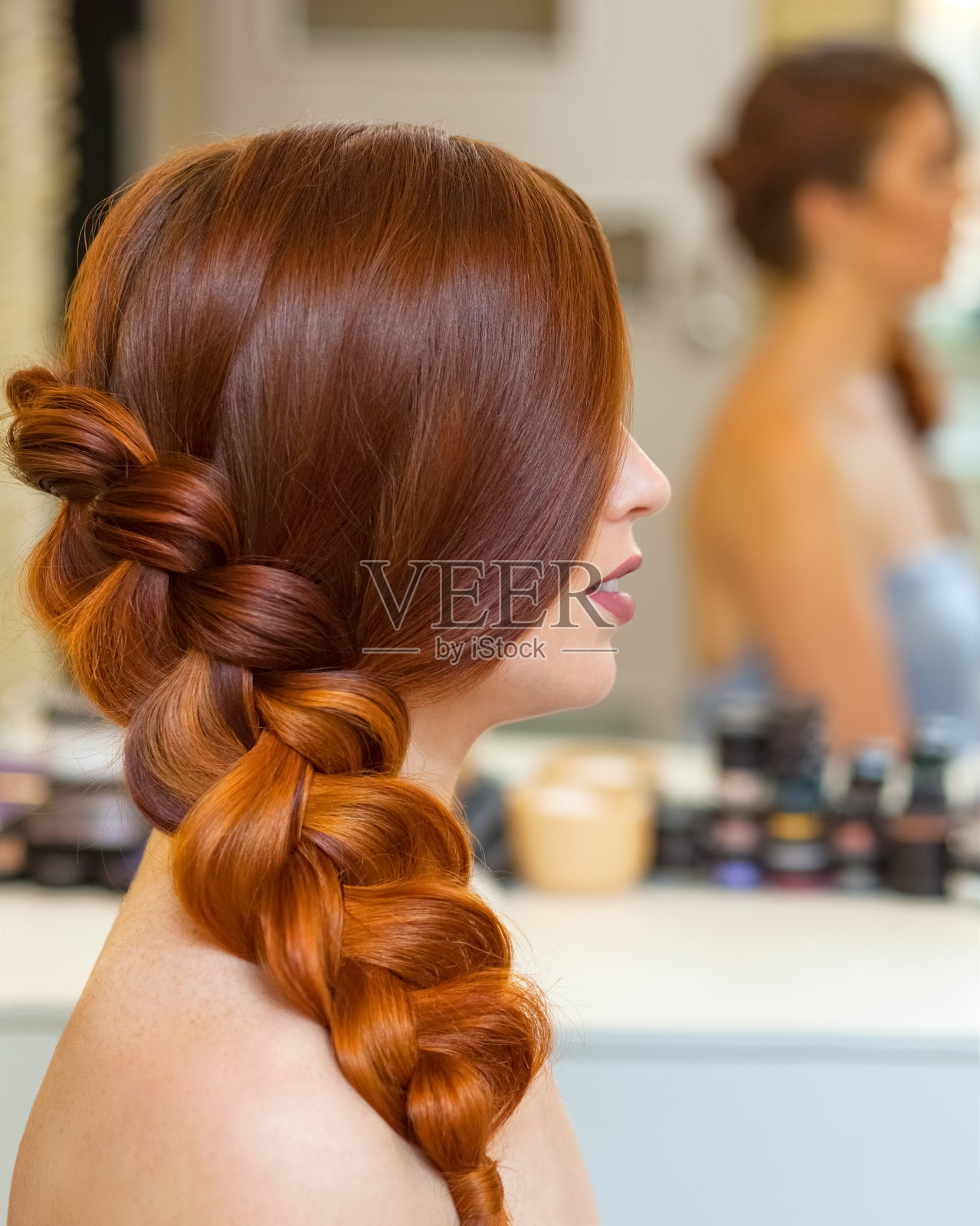 一个漂亮的女孩，一头长长的红发，梳着一个法式辫子，正在美容院里。照片摄影图片