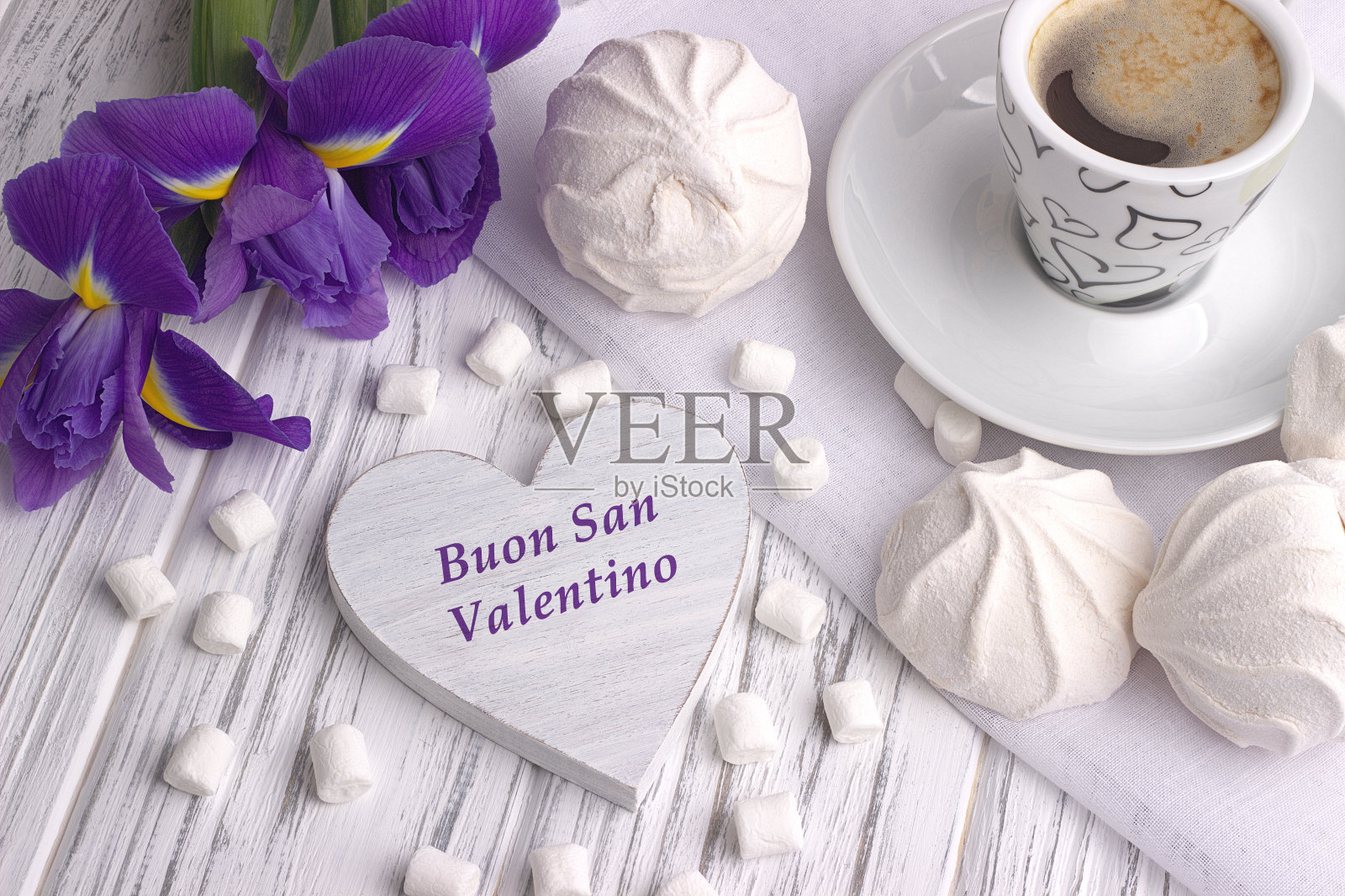 静物与一杯咖啡、棉花糖、和风、鸢尾花、心形符号与字母在白色木质背景上的意大利情人节快乐。照片摄影图片