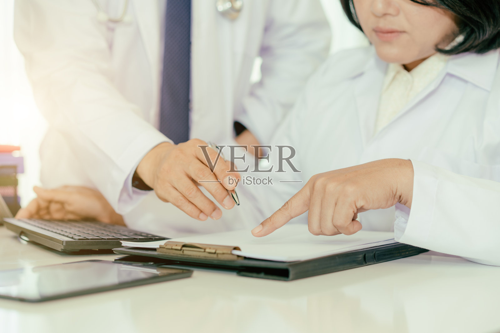现代医院两名医生对病案进行分析咨询。亚洲医生正在谈论报告。照片摄影图片