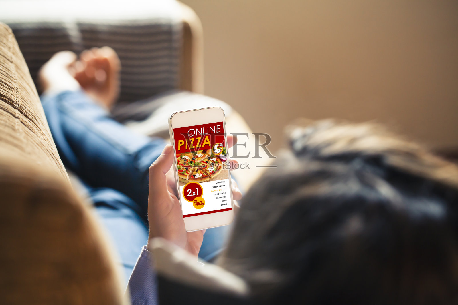 一名女子手持手机，屏幕上显示着披萨店的网站。照片摄影图片