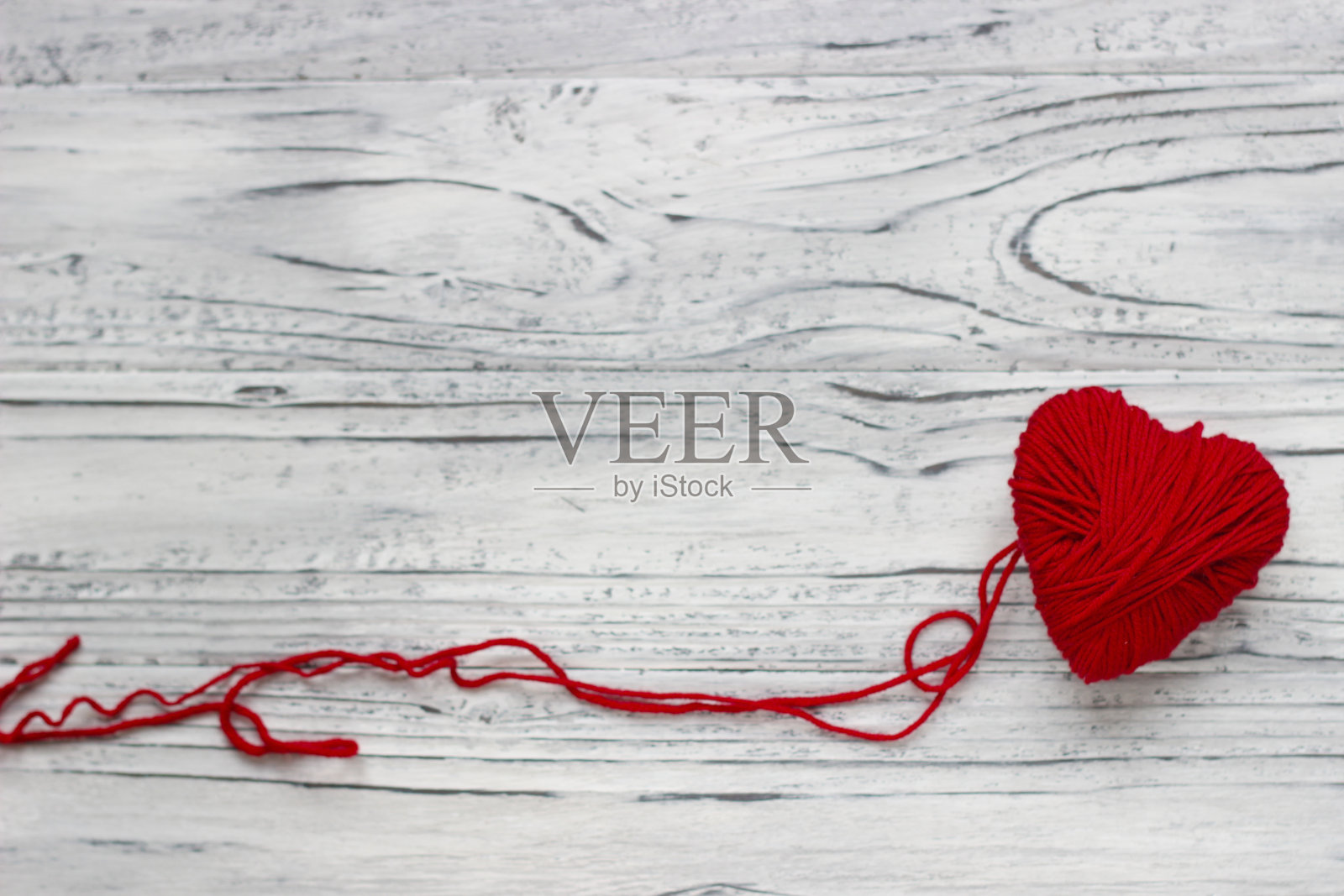 心形是一串线的形状，红色的毛衣就是从它上面织出来的。情人节的概念。照片摄影图片
