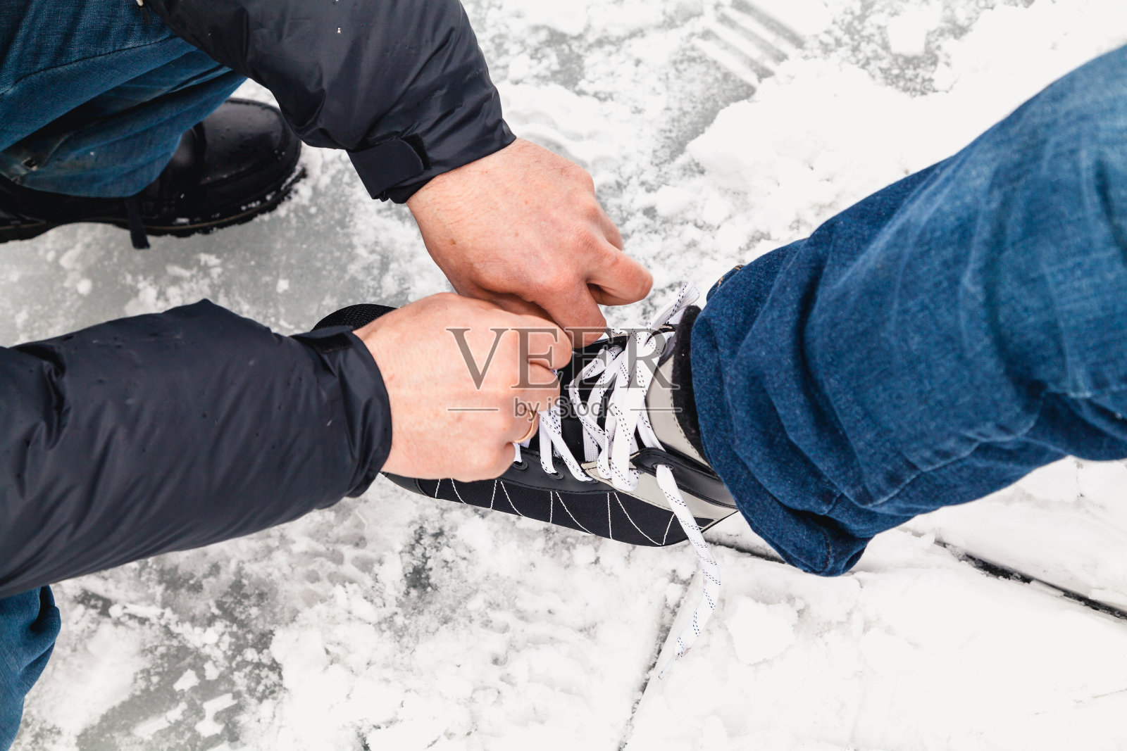 男人用手解开女人冰鞋上的绳子照片摄影图片
