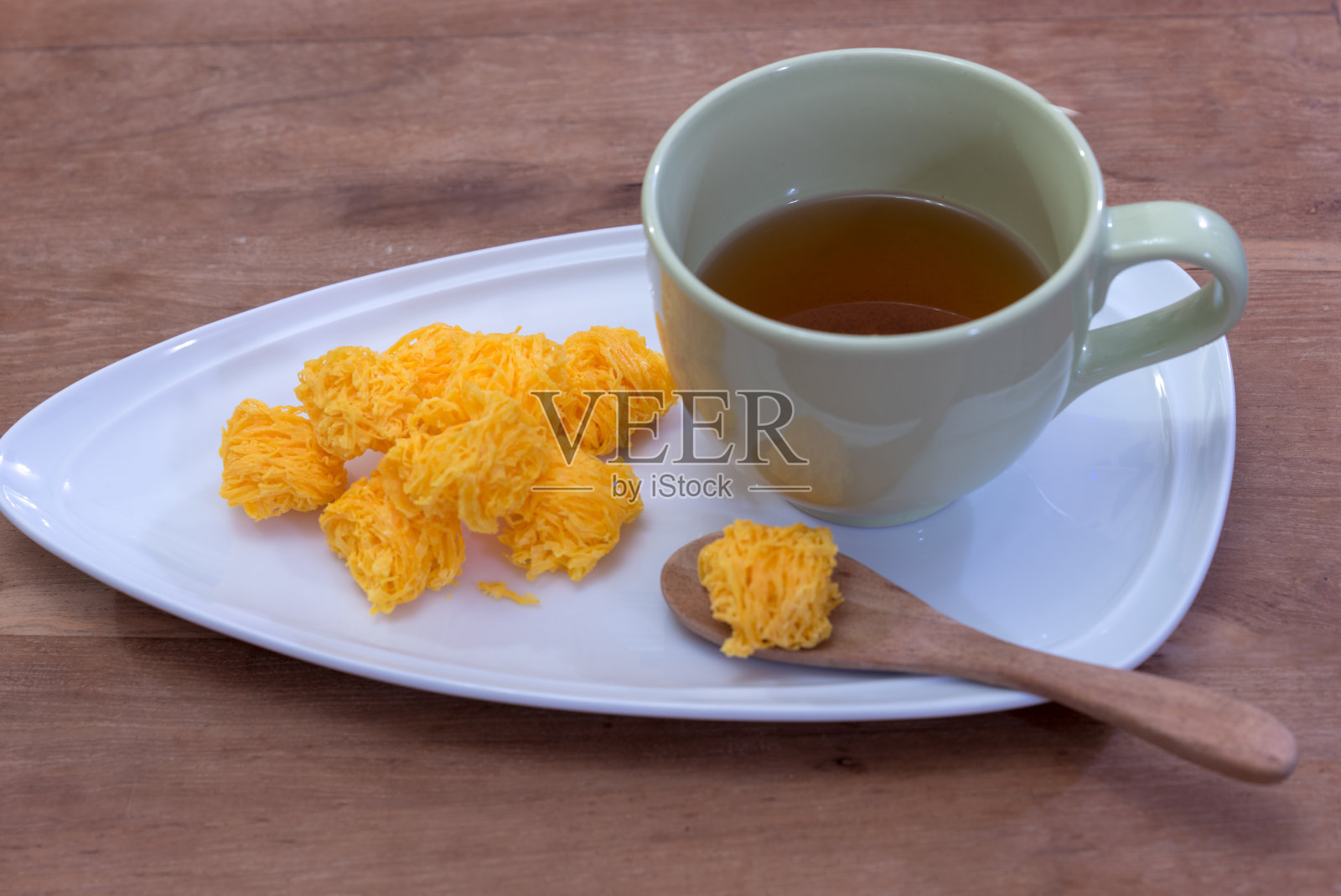 甜蛋松(Foi Thong)在白色的盘子和棕色的茶在绿色的杯子放在木桌上照片摄影图片