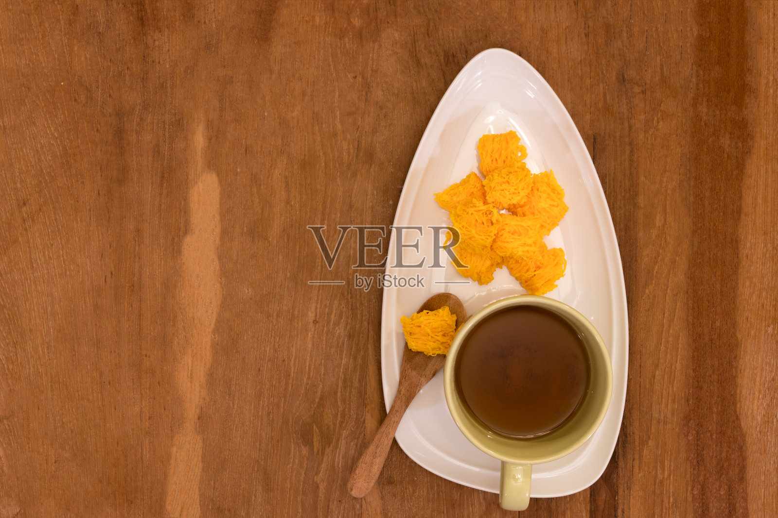 甜蛋松(Foi Thong)在白色的盘子和棕色的茶在绿色的杯子放在木桌上照片摄影图片