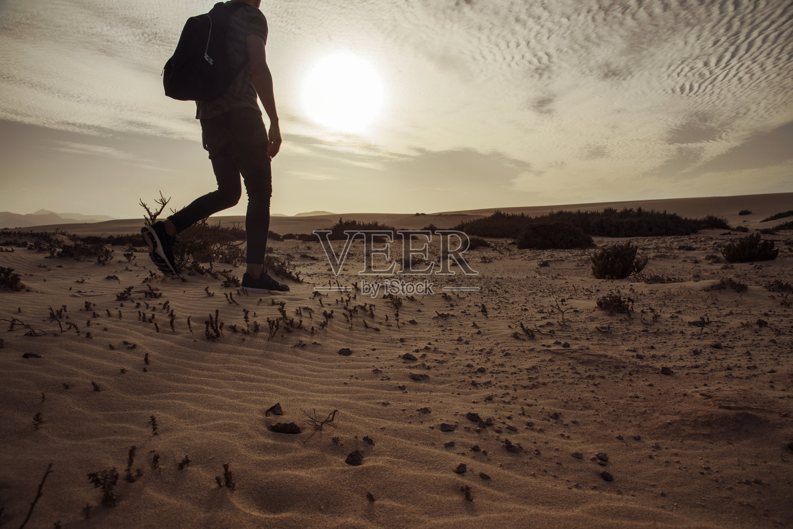 背着背包走在沙漠里的人照片摄影图片
