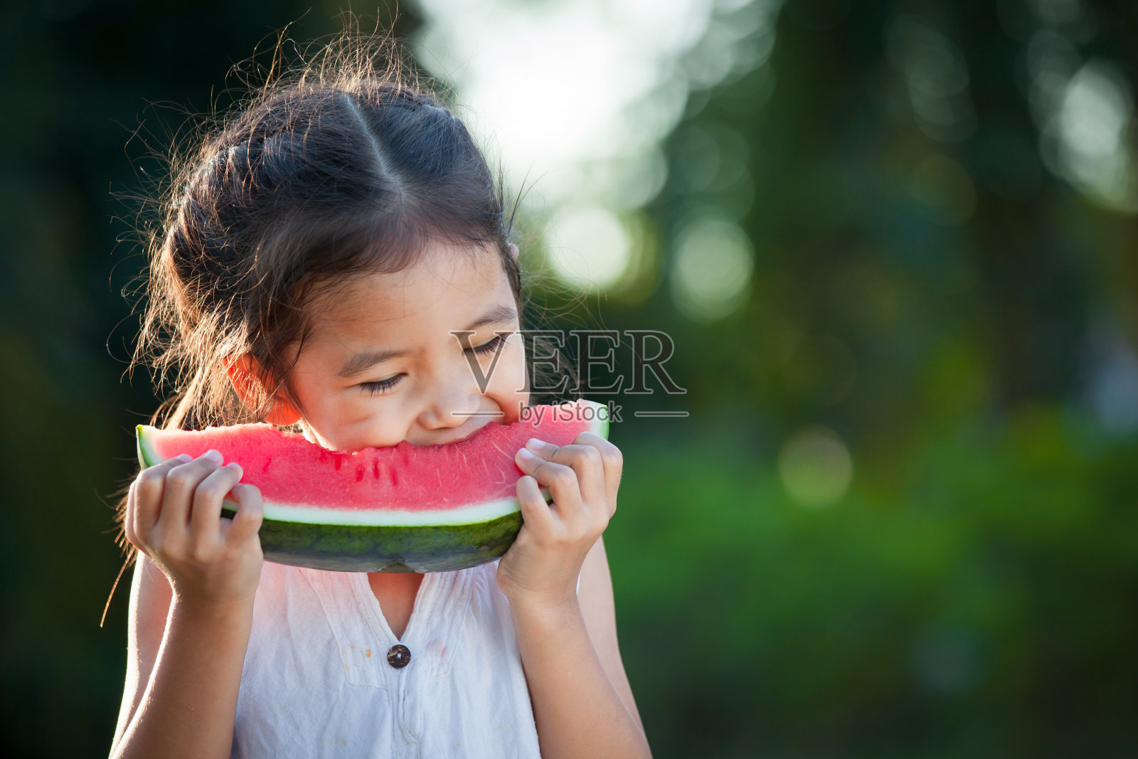 可爱的亚洲小女孩吃西瓜新鲜水果在花园里照片摄影图片