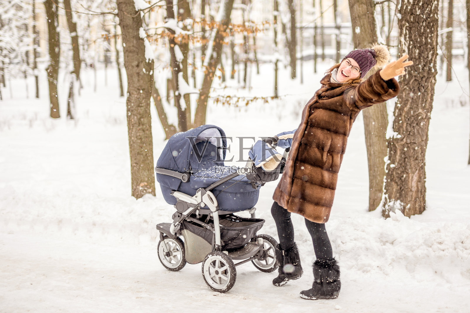 女人在冬天跳舞，推着婴儿车。照片摄影图片