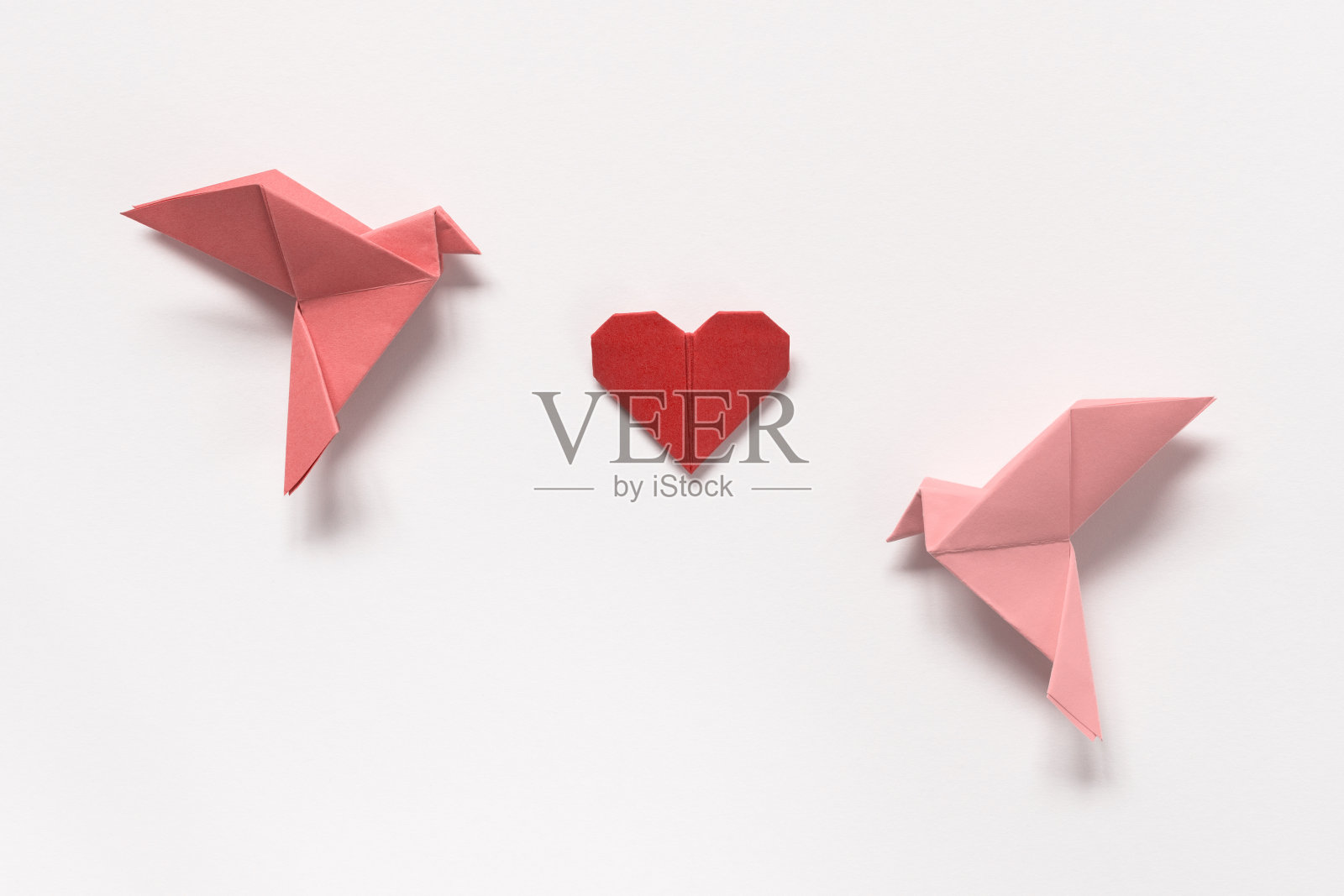 粉红色的鸟和红心折纸在白色的背景。情人节礼物卡。照片摄影图片