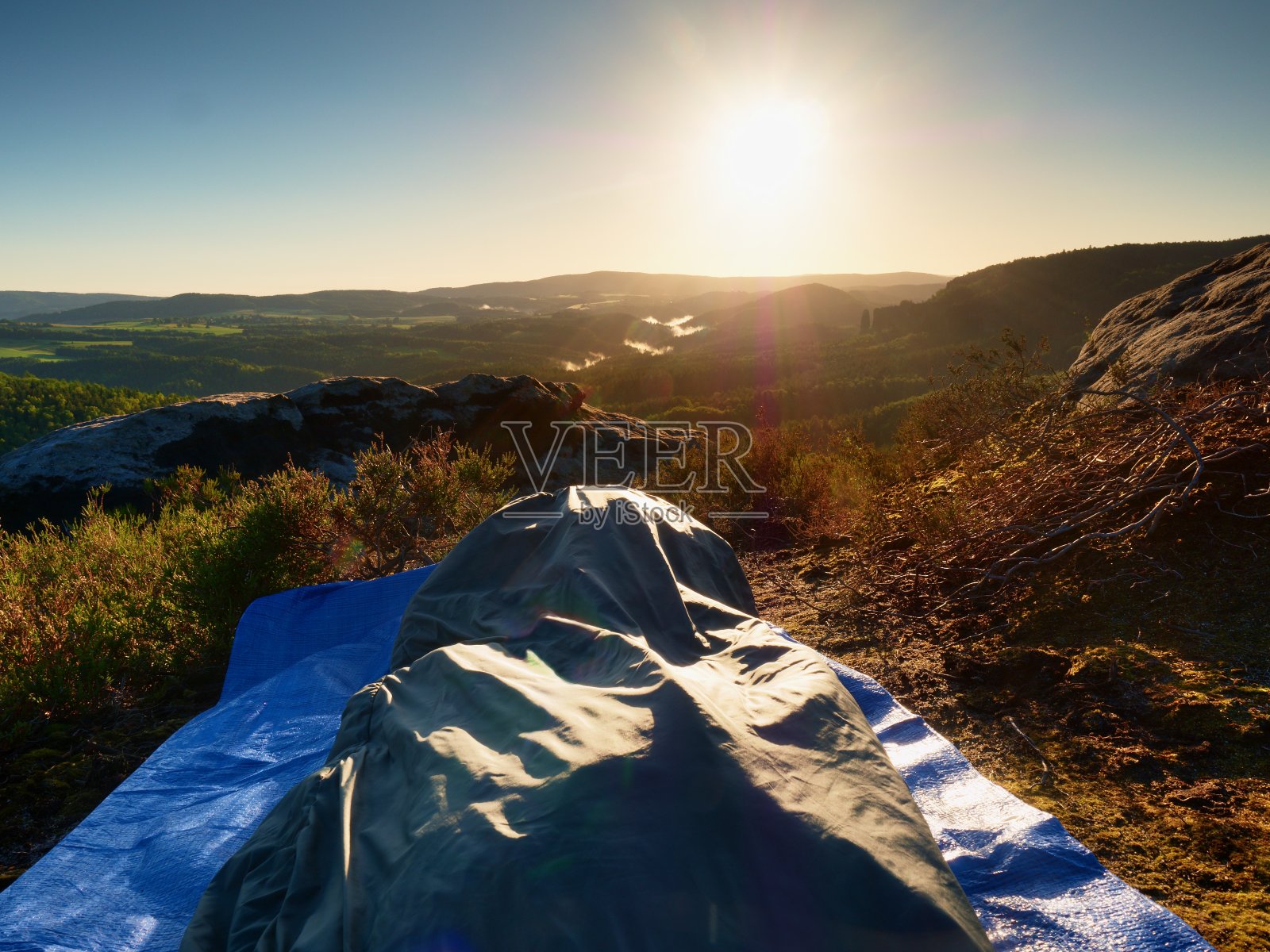 在岩架上的睡袋里美丽的醒来。鸟儿在歌唱，太阳在地平线上。照片摄影图片
