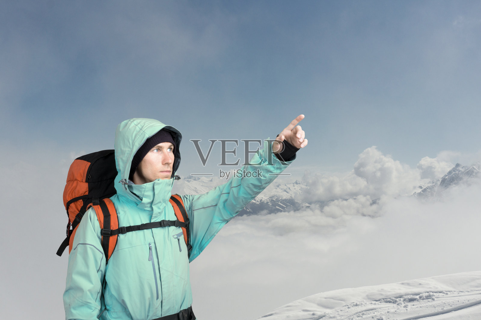 登山家指着山顶，站在一个冬季的山景照片摄影图片