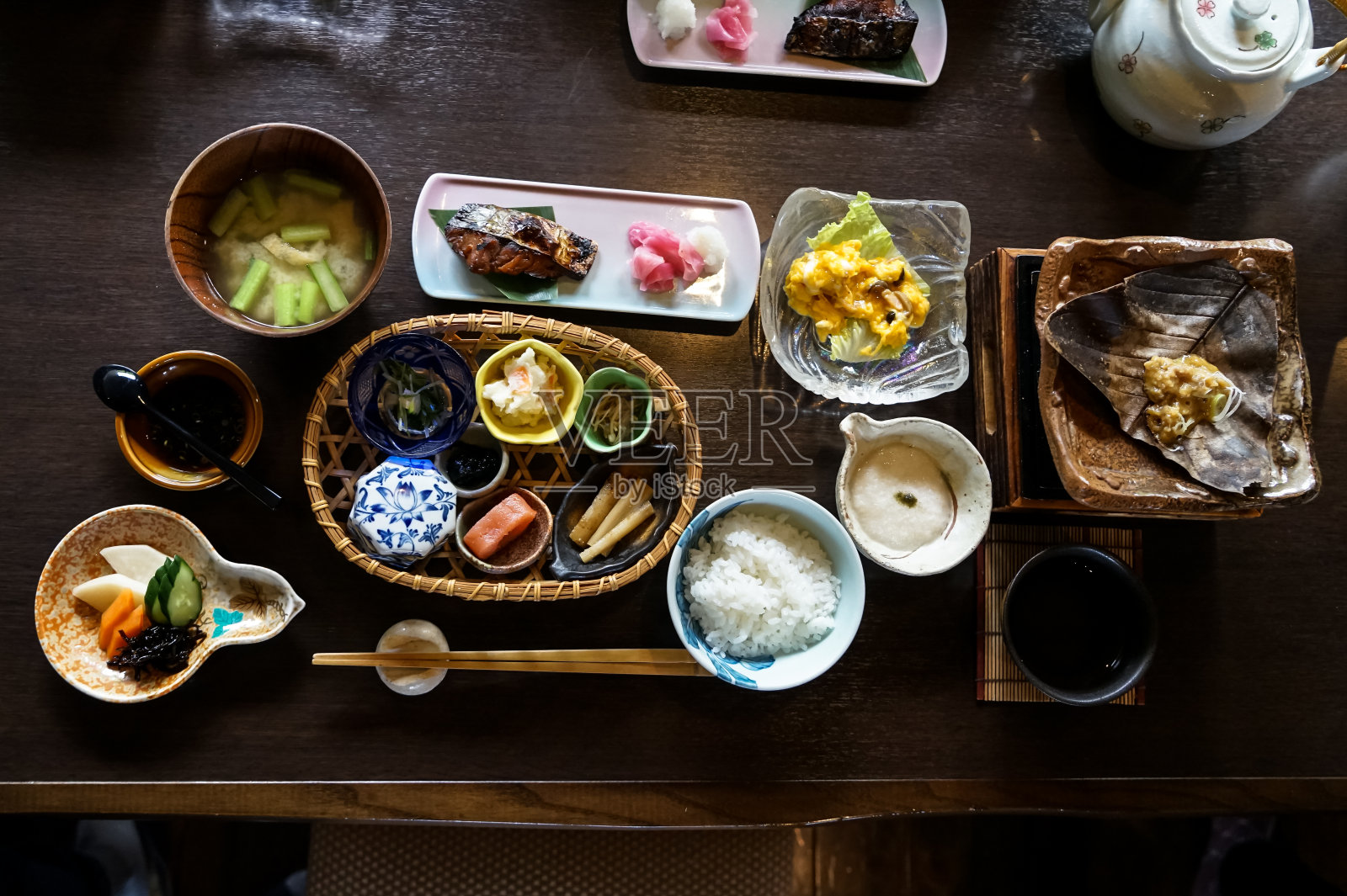 日本日式早餐包括白米饭，烤鱼，煎蛋，汤，门太子，泡菜，海藻，热盘，其他配菜和茶几上的绿茶照片摄影图片