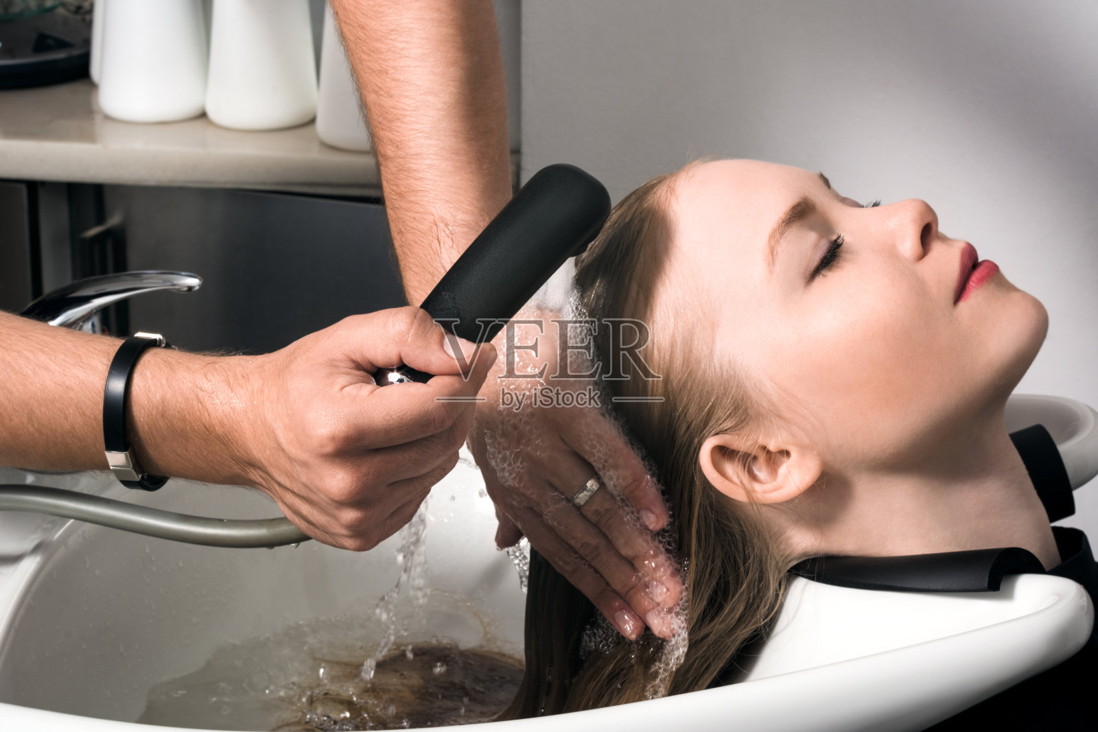 一位年轻女子在美容院洗头。照片摄影图片