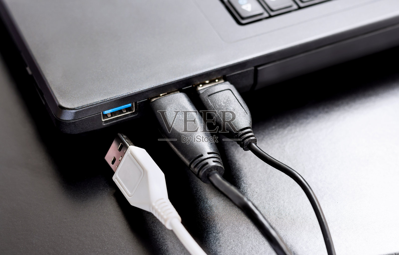 连接USB线到黑色书桌上的笔记本电脑。照片摄影图片