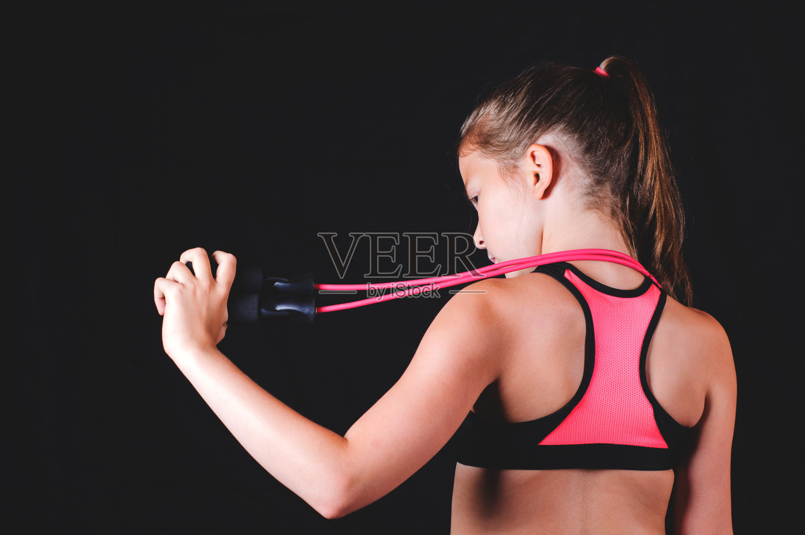 年轻的健身女孩与跳绳在黑色的背景。运动或健康的生活方式概念照片摄影图片