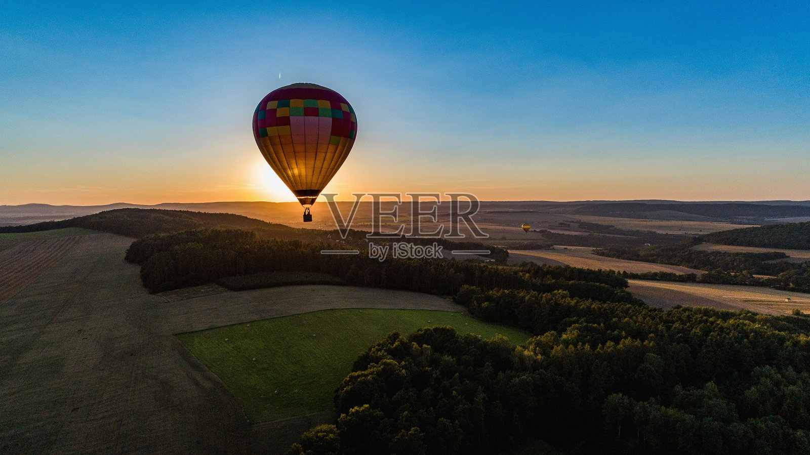 鸟瞰图的乡村与一个飞行的气球在夕阳的背光。照片摄影图片